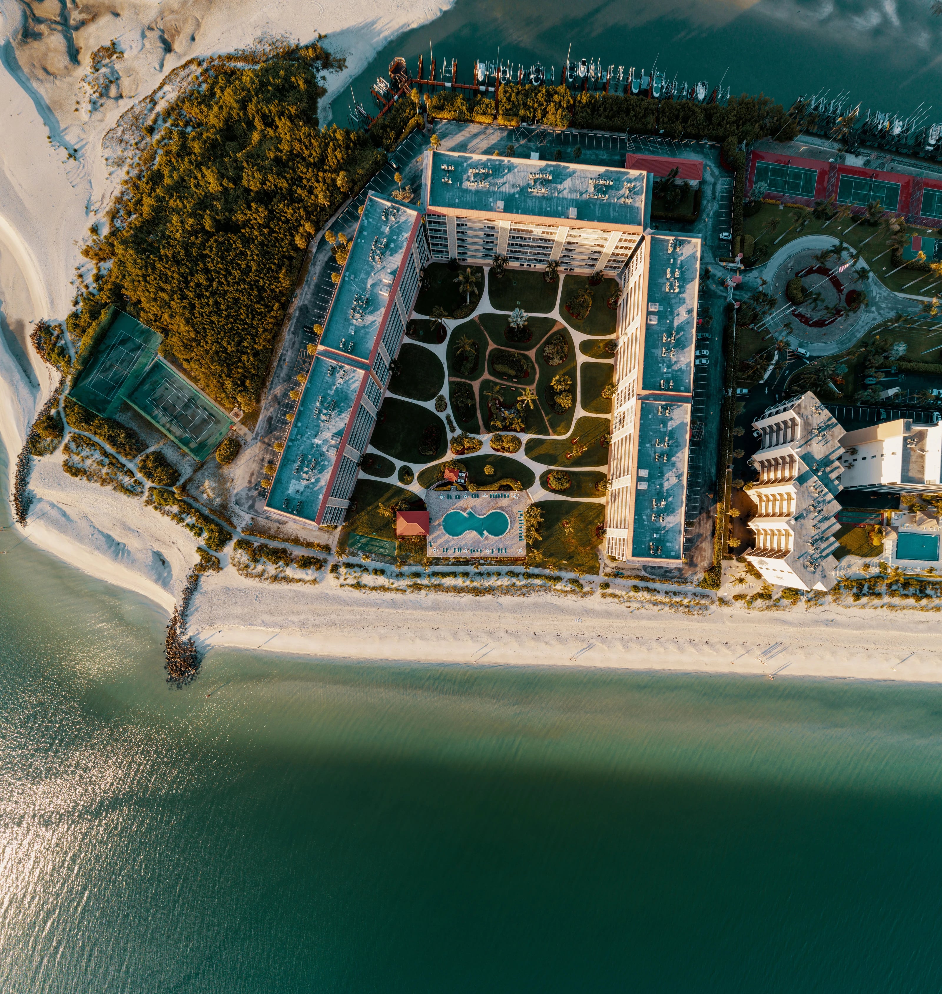 Aerial view of beachfront buildings, a pool and the shoreline in Bonita Springs
