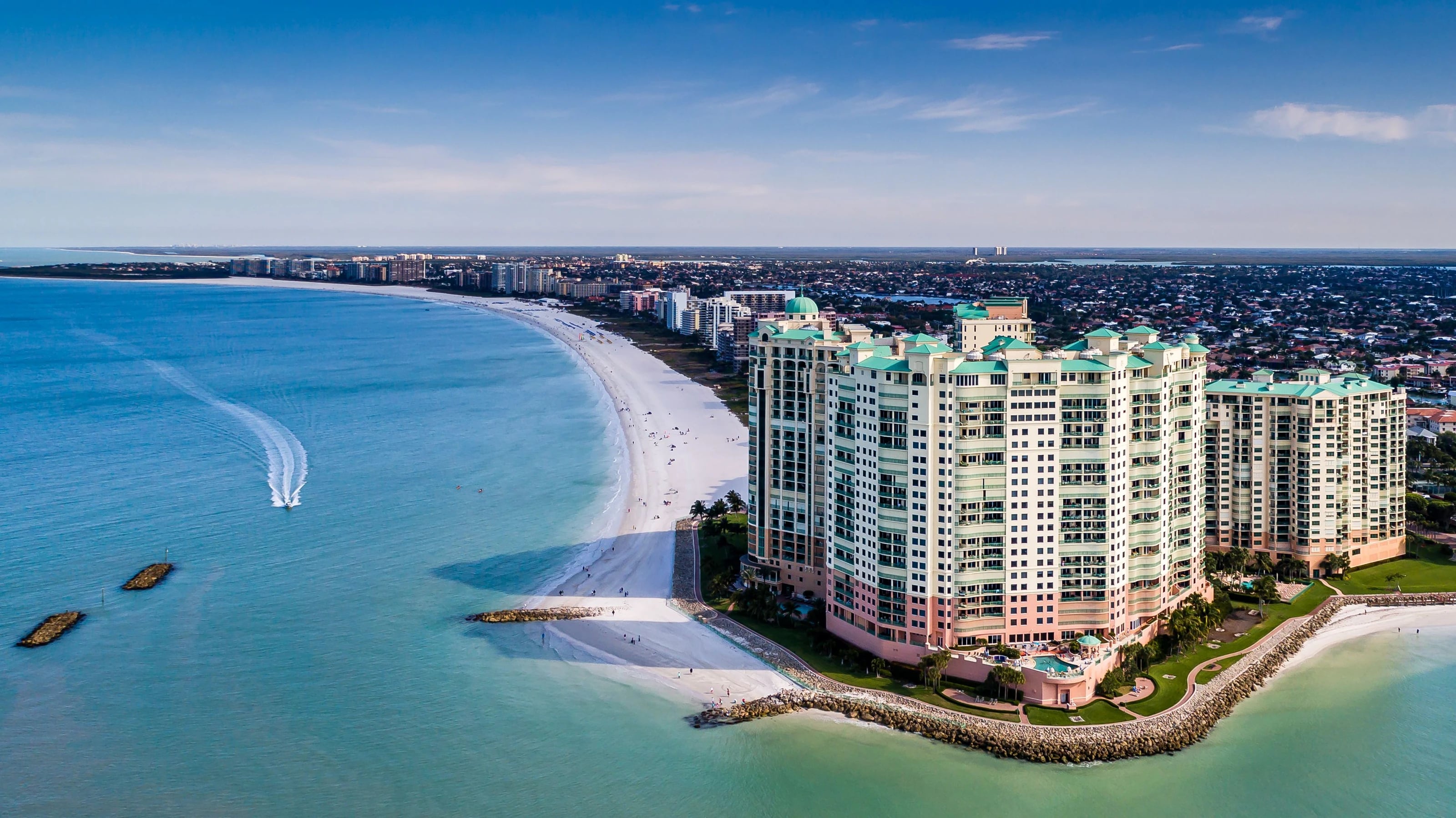 Marco Island beachfront buildings beside white sand and blue Gulf waters
